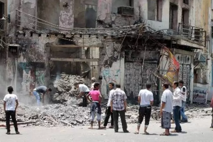 Iemenitas observam a retirada dos escombros de um prédio supostamente atacado por rebeldes xiitas huthis em Áden (Saleh al-Obeidi/AFP)