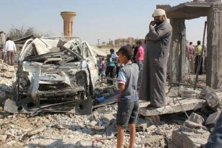 Sírios observam local de ataque aéreo em Raq: governo sírio tem lançado ataques frequentes na cidade e outras posições do EI no norte e leste da Síria (STR/AFP)