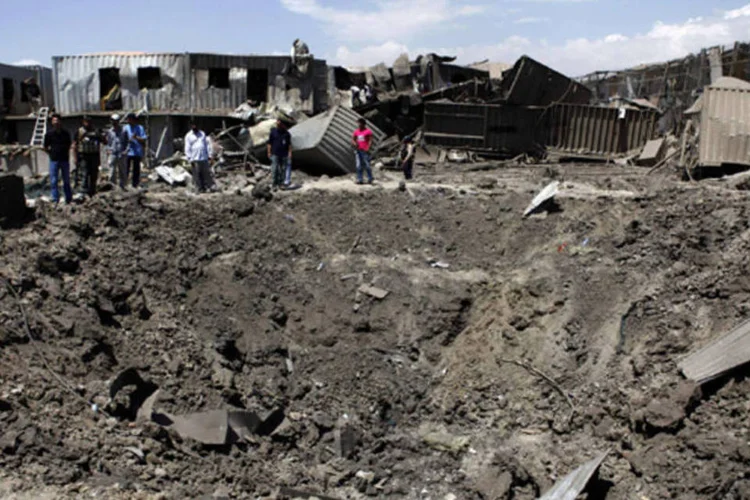 Pessoas ao lado do local onde ocorreu ataque: atentado detonou uma explosão que deixou uma cratera de seis metros de profundidade e cerca de 15 metros de largura (Mohammad Ismail/Reuters)