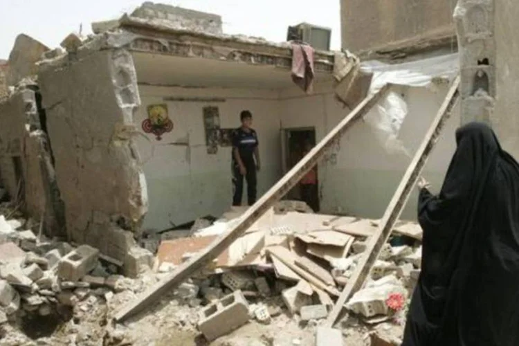 Moradores inspecionam o local de explosão de uma bomba no distrito de al-Wahda na periferia de Bagdá (Ali al-Mashhadani/Reuters)