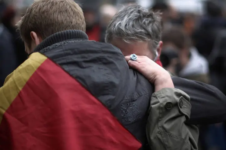
	Pessoas choram ap&oacute;s atentado em Bruxelas com bandeira da B&eacute;lgica
 (Christopher Furlong / Getty Images)