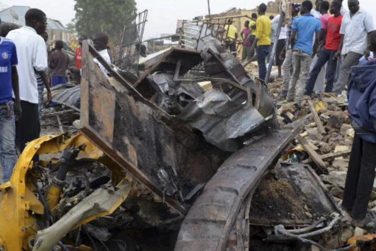Pessoas olham a um mercado danificado após uma explosão em Ajilari-Gomari, no estado de Borno, Nigéria (Reuters)