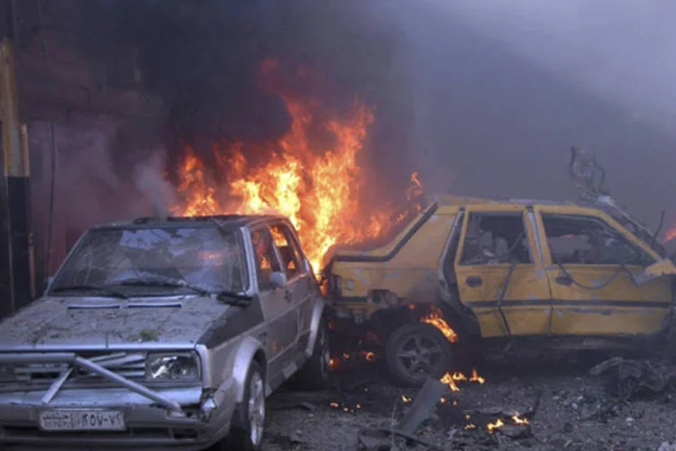 Carros queimam após as explosões de dois carros-bomba na área de Karam al-Loz, em Homs, na Síria (SANA/Divulgação via Reuters)