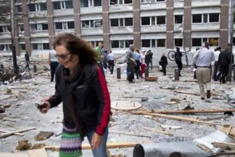 Mulher caminha entre escombros em Oslo: atentados podem estar ligados (AFP)