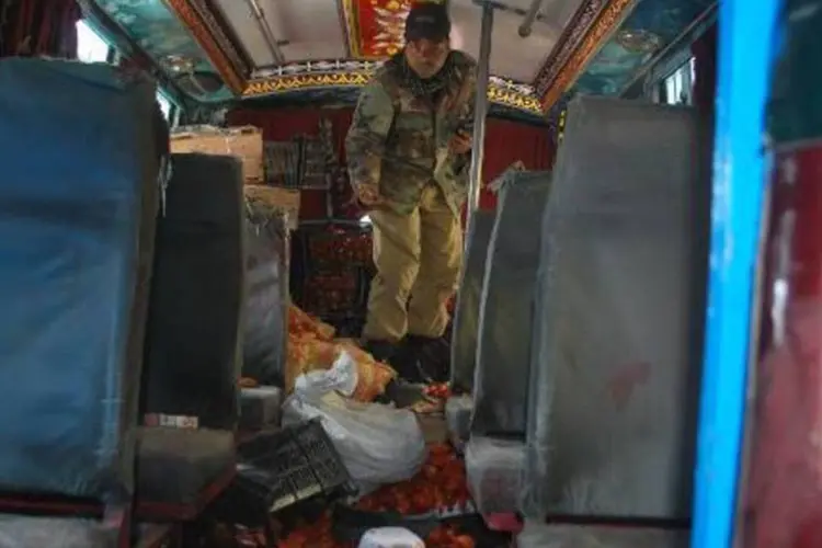 Policial paquistanês inspeciona micro-ônibus após ataque de homens armados que deixou oito mortos no sudoeste do país (Banaras Khan/AFP)