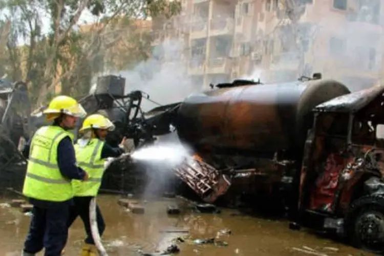 Bombeiros combatem as chamas após o atentado em Deir Ezzor (AFP)