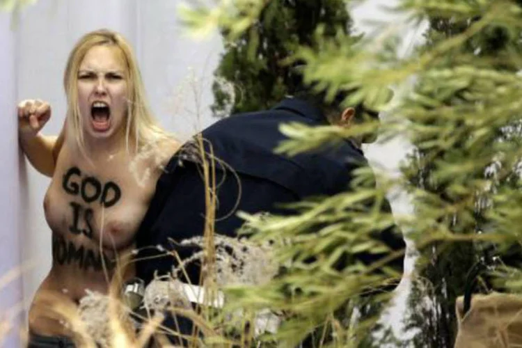 Ativista do grupo Femen protesta em presépio da Praça São Pedro com os seios descobertos e a frase "God is woman" (Deus é mulher) (Vincenzo Livieri/AFP)