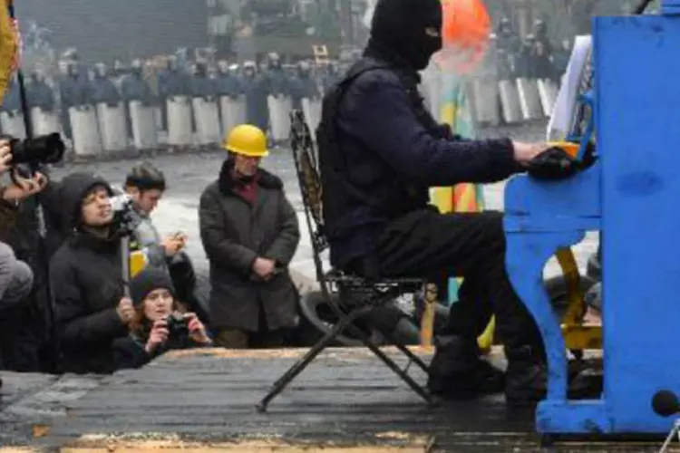 Ativista opositor encapuzado toca piano na barricada: depois do músico, que tocou encapuzado, se apresentaram outros jovens músicos e a cantora Rouslana (AFP)