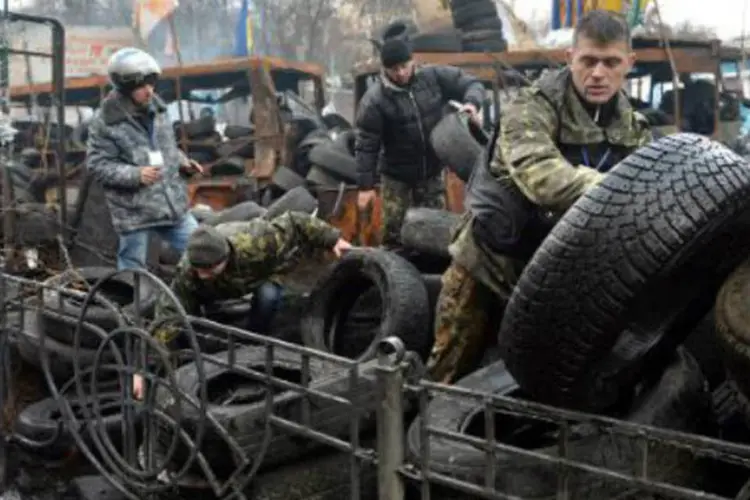 Ativistas ucranianos erguem barricadas com pneus em rua de Kiev: mais de 200 manifestantes atacaram durante a manhã a sede do partido (Sergei Supinsky/AFP)
