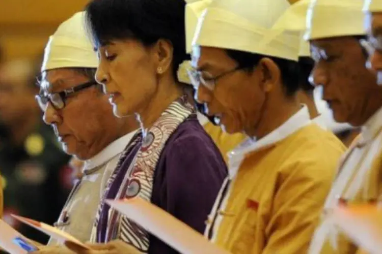 Aung San Suu Kyi lê o juramento no Parlamento ao lado dos deputados de seu partido (Soe Than Win/AFP)