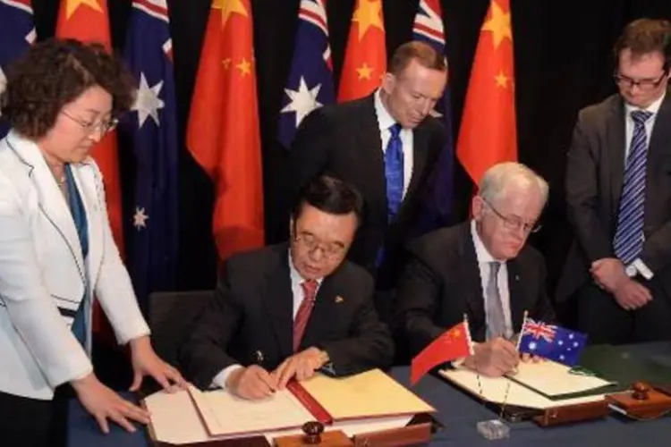 
	O ministro australiano do Comercio, Andrew Robb, e seu colega chin&ecirc;s, Gao Huchen assinam o acordo: em 2014, a China se converteu no primeiro investidor estrangeiro na Austr&aacute;lia, ficando &agrave; frente dos EUA
 (AFP/ LUKAS COCH)