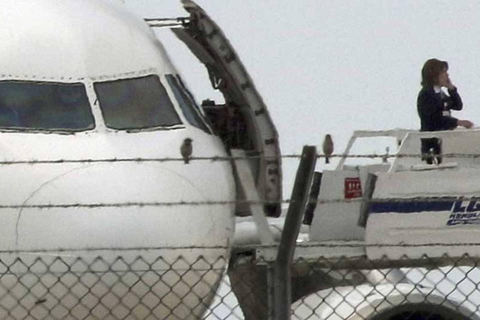 Uma autoridade telefona próximo ao avião sequestrado no Egito e que aterrissou no Chipre (Yiannis Kourtoglou/Reuters)