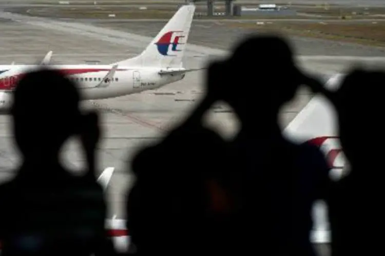 Crianças observam um avião da Malaysia Airlines: ausência de chamadas ou de e-mails pode ser um indício (Manan Vatsyayana/AFP)