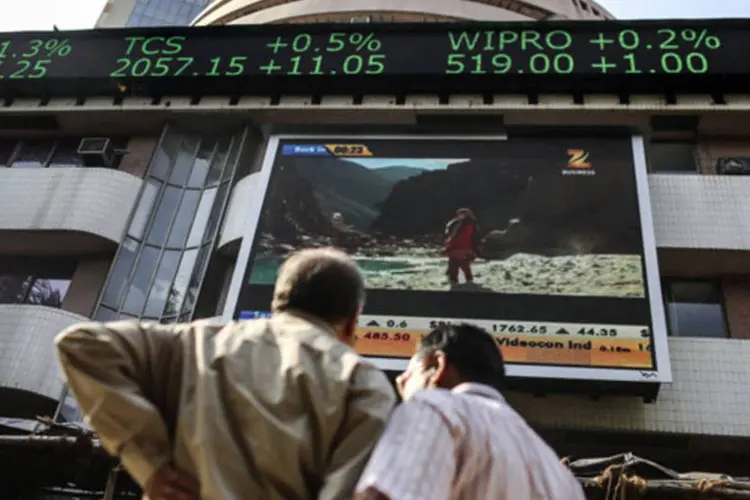 Homens em frente a um telão que indica ações no Bolsa de Valores de Bombaim, na Índia (Dhiraj Singh/Bloomberg)