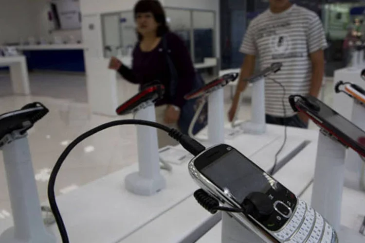
	Consumidores olham celulares &agrave; venda em uma loja da Telcel, da Am&eacute;rica M&oacute;vil, na Cidade do M&eacute;xico: companhia disse que o lucro no per&iacute;odo de janeiro a mar&ccedil;o caiu 48,3 por cento
 (Susana Gonzalez/Bloomberg)