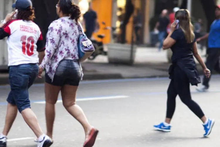 
	Pessoas falando no celular atravessam uma rua em Ipanema, Rio de Janeiro
 (Lianne Milton/Bloomberg)