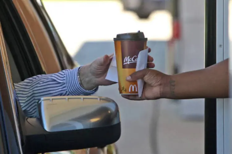Funcionária do McDonald's entrega um café para um consumidor do drive-thru em um restaurante da rede em Oak Brook, Illinois (Tim Boyle/Bloomberg)