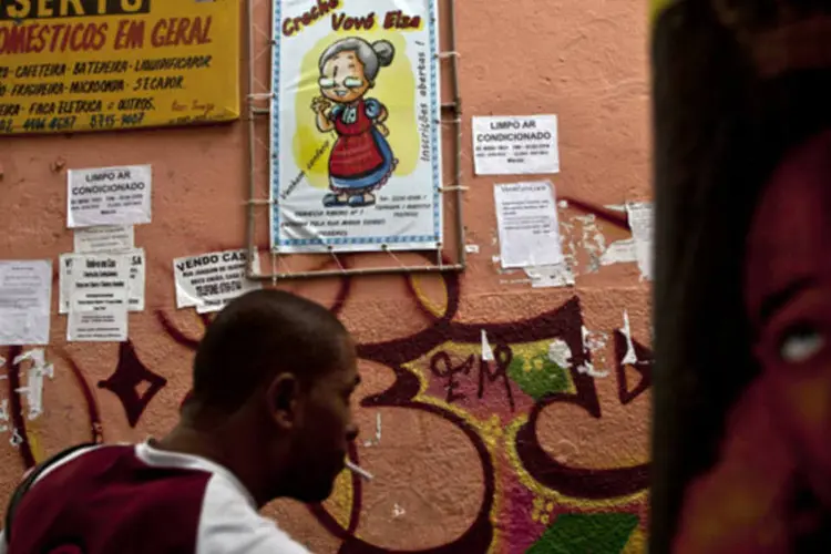 Homem passa por uma parede com uma série de anúncios de serviços no Complexo do Alemão, no Rio de Janeiro (Dado Galdieri/Bloomberg)