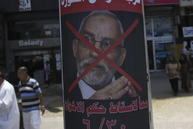 
	Pessoas passam ao lado de poster de Badie: a Promotoria ordenou nesta quinta-feira a deten&ccedil;&atilde;o de Badie e do&nbsp;&quot;n&uacute;mero dois&quot;&nbsp;da Irmandade, Jairat al Shater
 (Amr Abdallah Dalsh/Reuters)