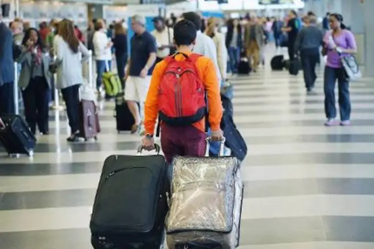 
	Homem carrega bagagens: o n&uacute;mero, no entanto, mostra queda no ritmo anual de expans&atilde;o, que foi 6,5% em 2013
 (Scott Olson/AFP)