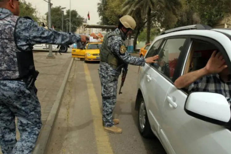 Policiais federais iraquianos inspecionam veículo em frente aos prédios do governo, em Bagdá (AFP / Sabah Arar)