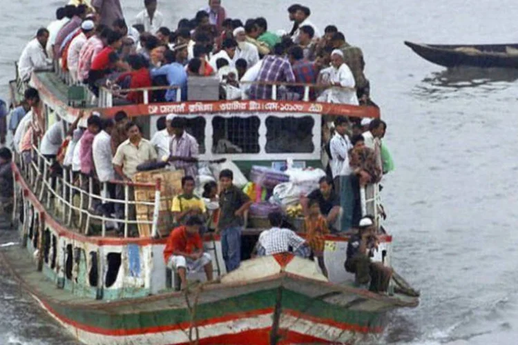 Barca lotada de pessoas navega pelo rio Buriganga em Daca, Bangladesh (©afp.com / Farjana K. Godhuly)