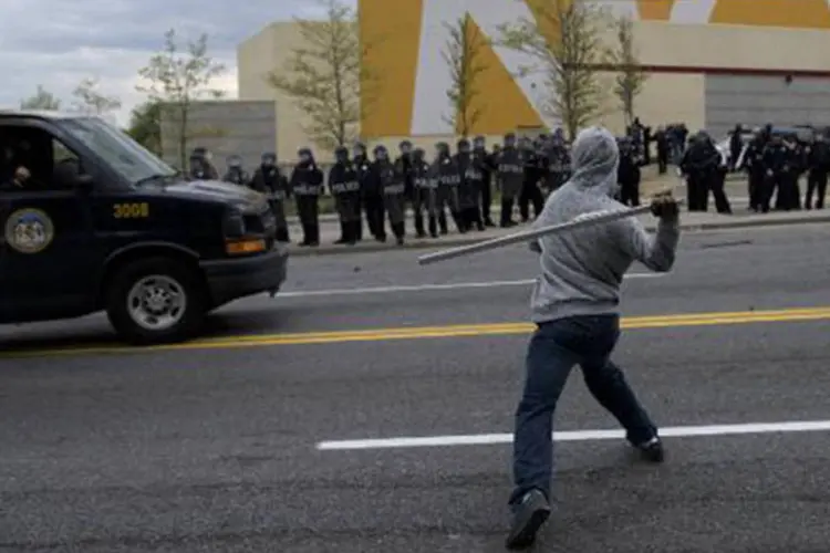 Manifestantes e policiais em confronto após funeral de jovem negro morto, em Baltimore, no dia 27 de abril de 2015
 (BRENDAN SMIALOWSKI/AFP)