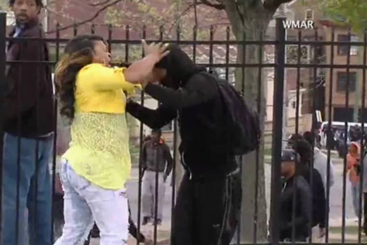 Mãe retira filho de distúrbios em Baltimore: ao ver o jovem jogando pedras em policiais pela televisão, mulher foi até o local onde ele estava e o estapeou até retirá-lo do local (Reprodução)