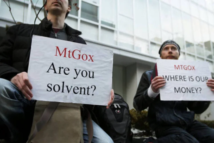 Manifestantes seguram cartazes durante um protesto em frente a sede do banco de bitcoins Mt.Gox, em Tóquio (Kiyoshi Ota/Bloomberg)