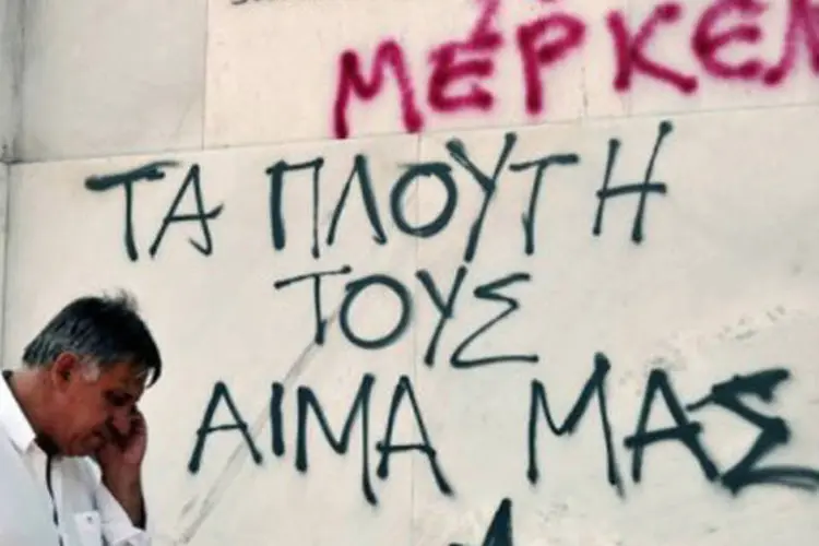 
	Parede do Banco Central grego pichada em protesto: as medidas controversas preveem novos cortes dos sal&aacute;rios, das aposentadorias e das ajudas sociais
 (Louisa Gouliamaki/AFP)
