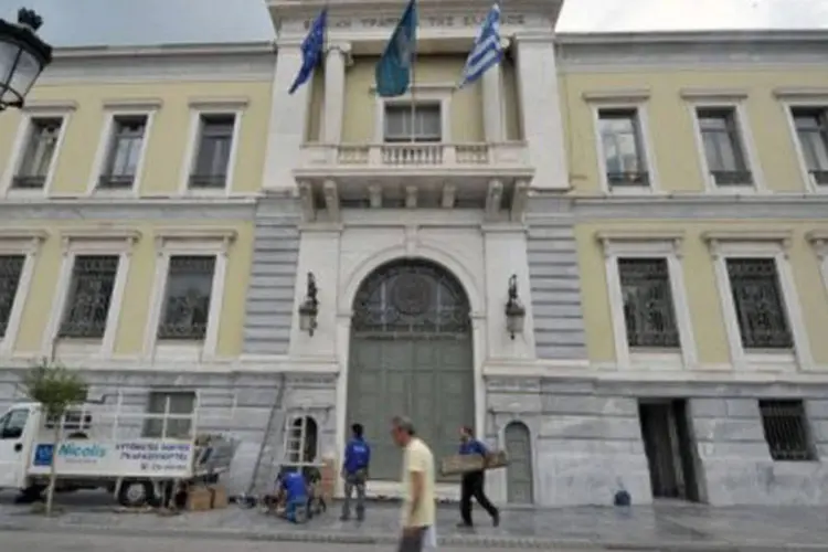 
	Homem passa pelo Banco Nacional da Gr&eacute;cia, em Atenas: a Gr&eacute;cia, que passou cinco anos consecutivos em recess&atilde;o, prev&ecirc; para 2013 uma nova queda no PIB
 (Louisa Gouliamaki/AFP)
