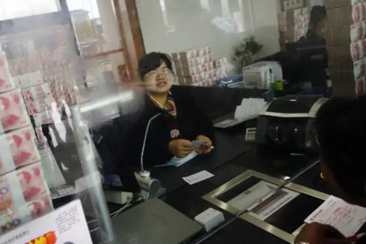 Funcionária do Jiangsu Sheyang Rural Commercial Bank conversa com um consumidor em uma das agências do banco em Yancheng, na China (Carlos Barria/Reuters)