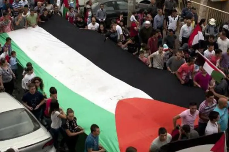 
	&Aacute;rabes israelenses seguram a bandeira palestina na cidade de Sakhnin, Israel
 (AFP/ Ahmad Gharabli)