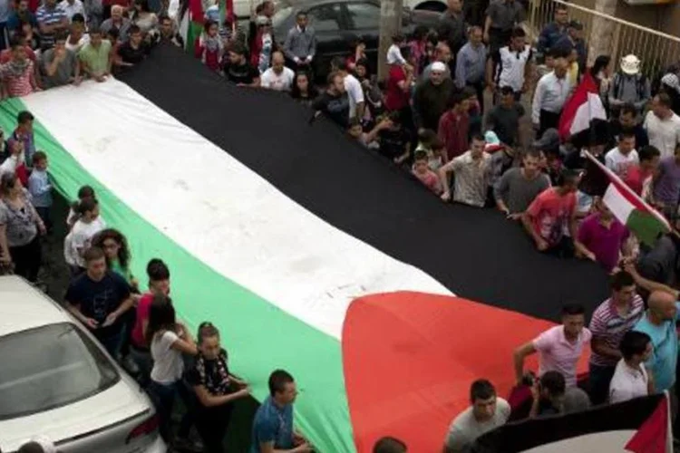 
	&Aacute;ranes-israelenses seguram bandeira palestina: o museu est&aacute; em uma antiga casa &aacute;rabe, rodeado por um pomar, em Sakhnin, na Galileia, uma regi&atilde;o de Israel onde vivem israelenses judeus e &aacute;rabes
 (AFP/ Ahmad Gharabli)
