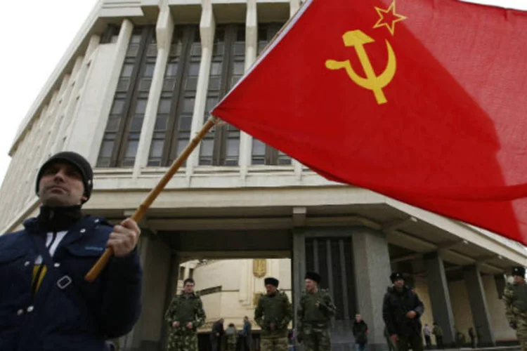 
	Homem segura bandeira da Uni&atilde;o Sovi&eacute;tica em frente ao parlamento da Crimeia: o referendo pode transferir o controle da regi&atilde;o da Ucr&acirc;nia para a R&uacute;ssia
 (David Mdzinarishvili/Reuters)
