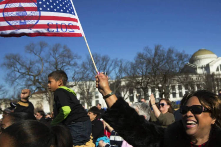 
	Mulher segura bandeira dos EUA: pessoas se re&uacute;nem para assistir ao juramento de posse do presidente Barack Obama em tel&atilde;o.
 (REUTERS/Shannon Stapleton)