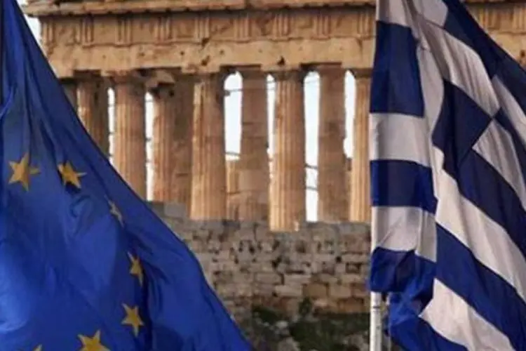 
	Bandeiras da Uni&atilde;o Europeia e da Gr&eacute;cia flamejam sobre o Minist&eacute;rio das Finan&ccedil;as da Gr&eacute;cia em Atenas: em carta a Tsipras, a at&eacute; hoje ministra adjunta qualificou o 3&ordm; resgate como uma &quot;capitula&ccedil;&atilde;o&quot;
 (Yannis Behrakis/Reuters)