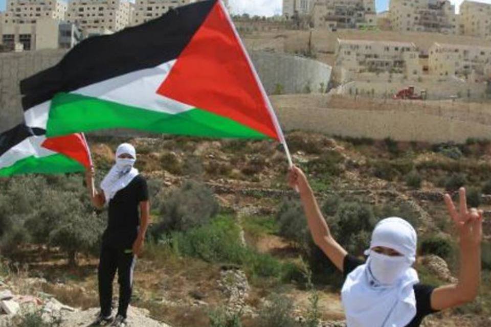 
	Manifestantes agitam bandeiras da Palestina em frente a um assentamento israelense
 (Musa al-Shaer/AFP)
