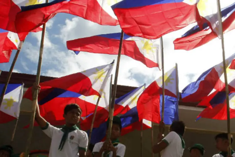 
	Crian&ccedil;as seguram bandeiras das Filipinas: al&eacute;m do problema da viol&ecirc;ncia, as elei&ccedil;&otilde;es nas Filipinas se caracterizam pela fraude e pela compra de votos
 (REUTERS/Cheryl Ravelo)