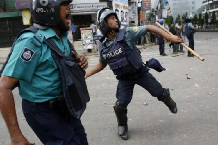 Policial atira um pedaço de tijolo durante confronto com militantes islamitas na frente da mesquita nacional em Daca, capital de Bangladesh ( REUTERS / Andrew Biraj)