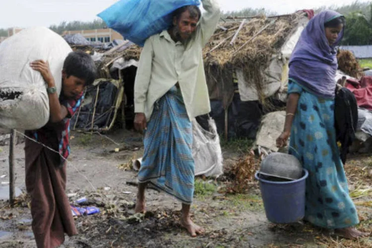 Família carrega seus pertences para abrigo após ter casa destruída por ciclone que atingiu Bangladesh (REUTERS)