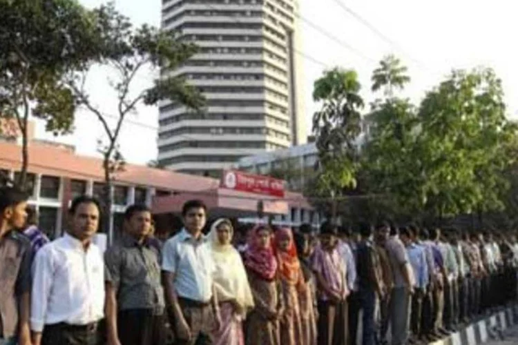 Funcionários formam uma corrente humana em frente ao Grameen Bank, em Daca. (Strdel/AFP)