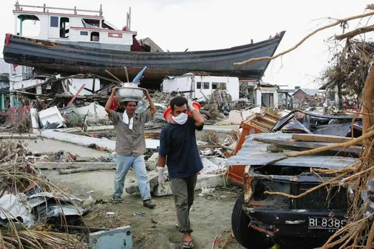 
	Pessoas deslocadas pelos tsunamis caminham em meio &agrave;s ru&iacute;nas em 4 de Janeiro de 2005, em Banda Aceh, na Indon&eacute;sia
 (Getty Images)