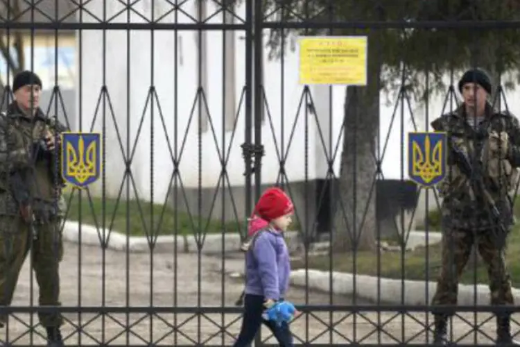 
	Garota passa em frente a uma base militar tomada por tropas russas na Crimeia
 (Alexander Nemenov/AFP)