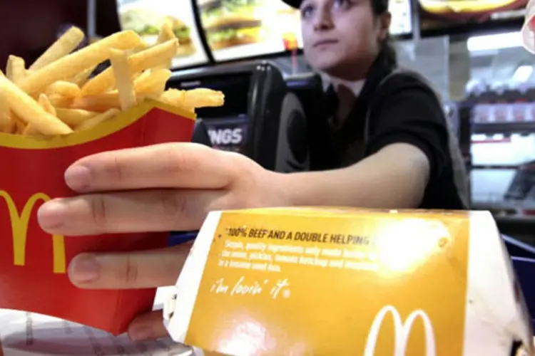 
	Funcion&aacute;ria do McDonald&#39;s servindo uma batata frita: pre&ccedil;os aumentaram cerca de 3% at&eacute; o final de junho
 (Jason Alden/Bloomberg)