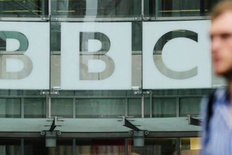 Homem passa na frente de um logotipo da BBC (Olivia Harris/Reuters)