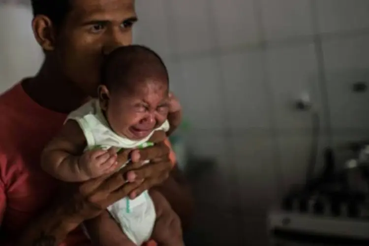 Matheus Lima segura seu bebê, Pietro, que sofre de microcefalia (CHRISTOPHE SIMON/AFP)
