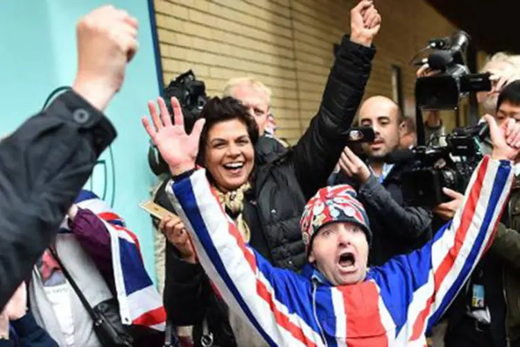 Vários cidadãos envolvidos em bandeiras britânicas e turistas curiosos se aproximaram das portas do hospital onde a filha de Kate nasceu (Ben Stansall/AFP)