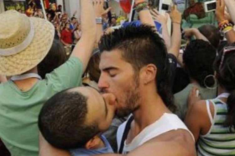 Homens se beijam enquanto o papamóvel passa ao fundo (Pedro Armestre/AFP)