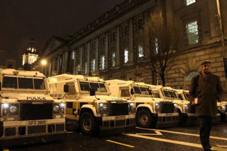 
	Carros da pol&iacute;cia irlandesa fazem uma barreira contra manifestantes durante uma reuni&atilde;o em Belfast: alguns manifestantes teriam atirado coquet&eacute;is molotov
 (Peter Muhly/AFP)